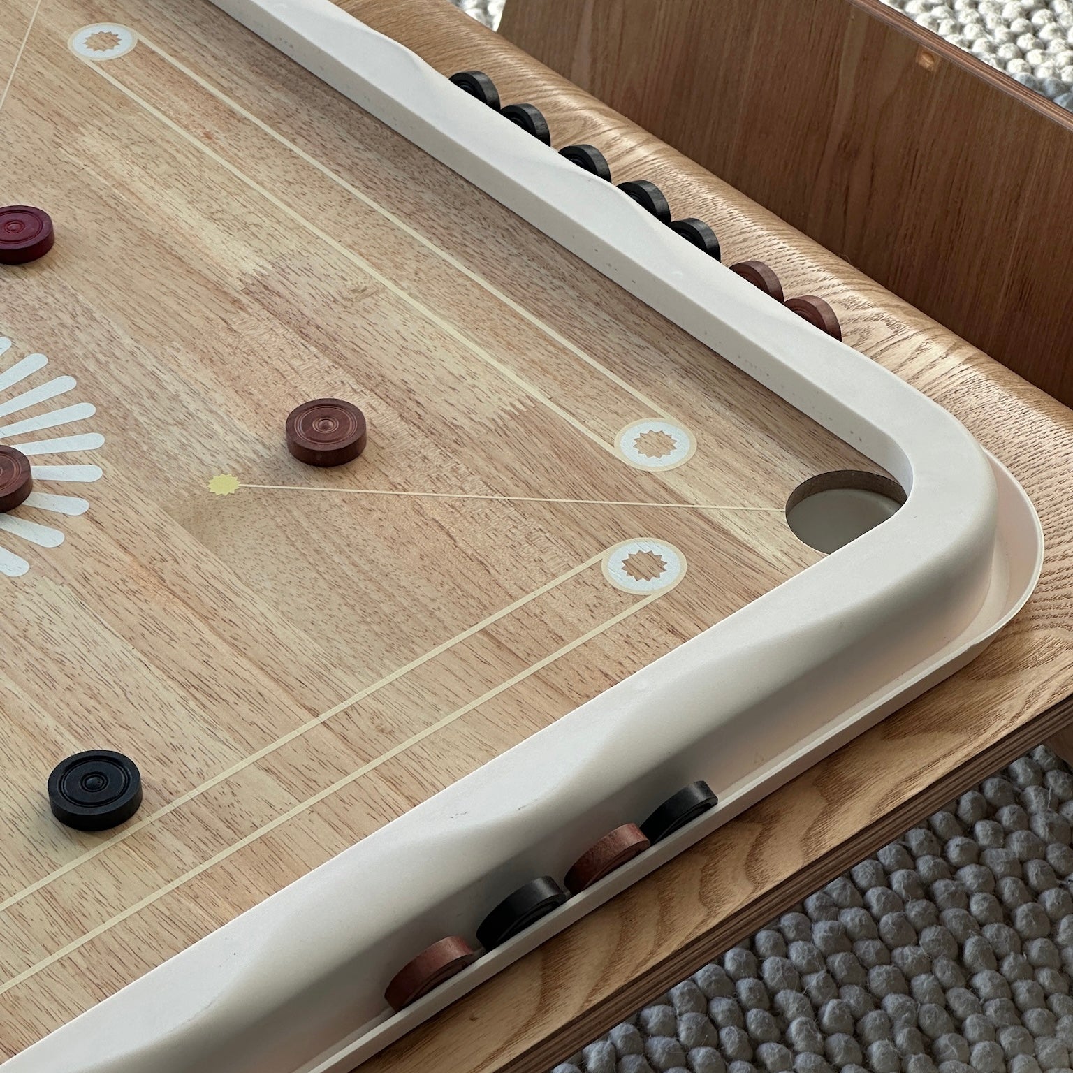 Wrap-around coin holder spotlighted on carrom board.